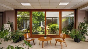 A room with a large sliding glass door, a round table with chairs, and various potted plants. - Interhotel Sandanski (Sandanski)