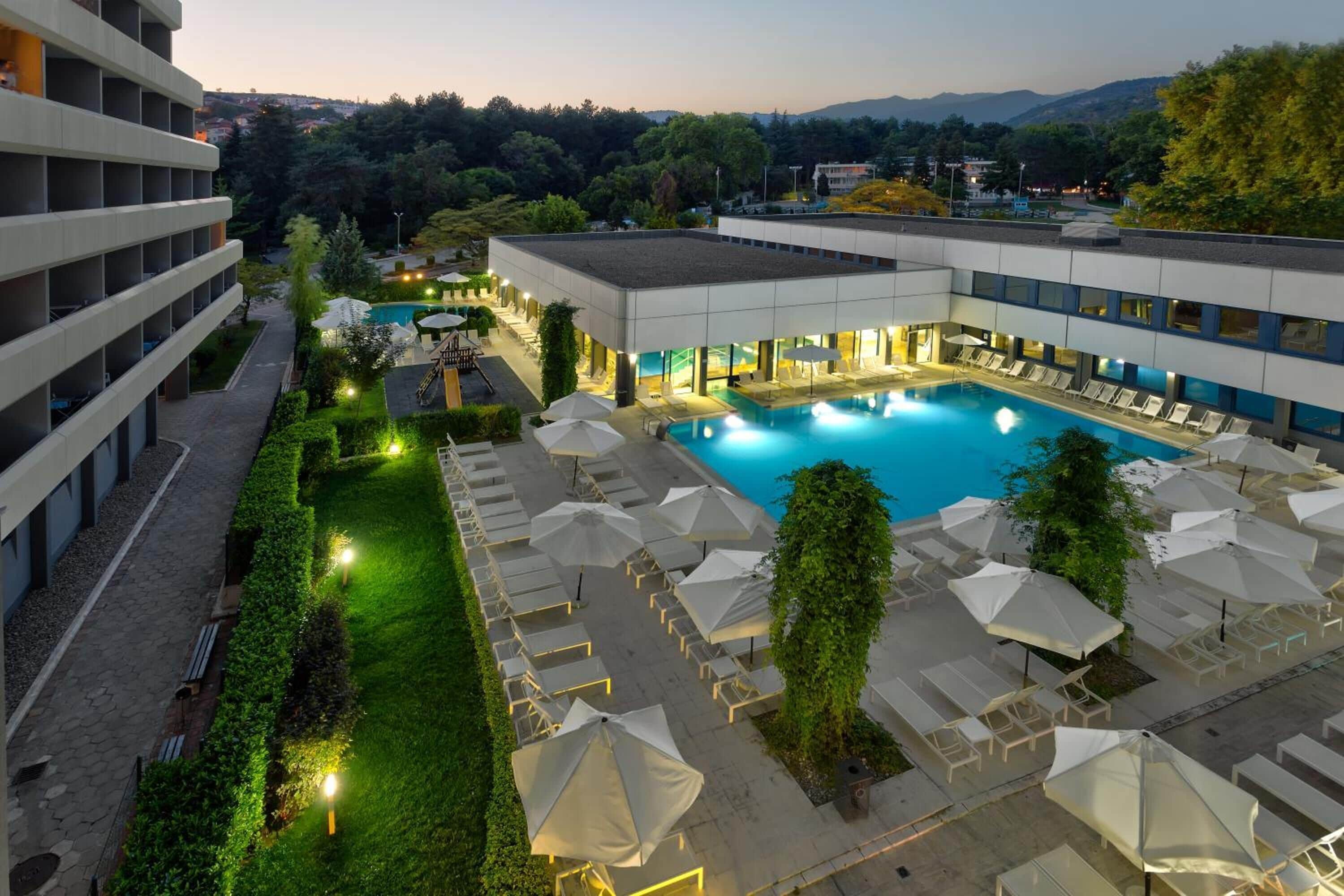 Una piscina techada, una piscina al aire libre, sombrillas