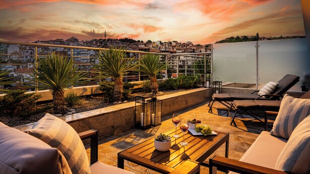 A rooftop terrace with a sunset view, outdoor seating, and a cityscape in the background. - Interhotel Sandanski (Sandanski)