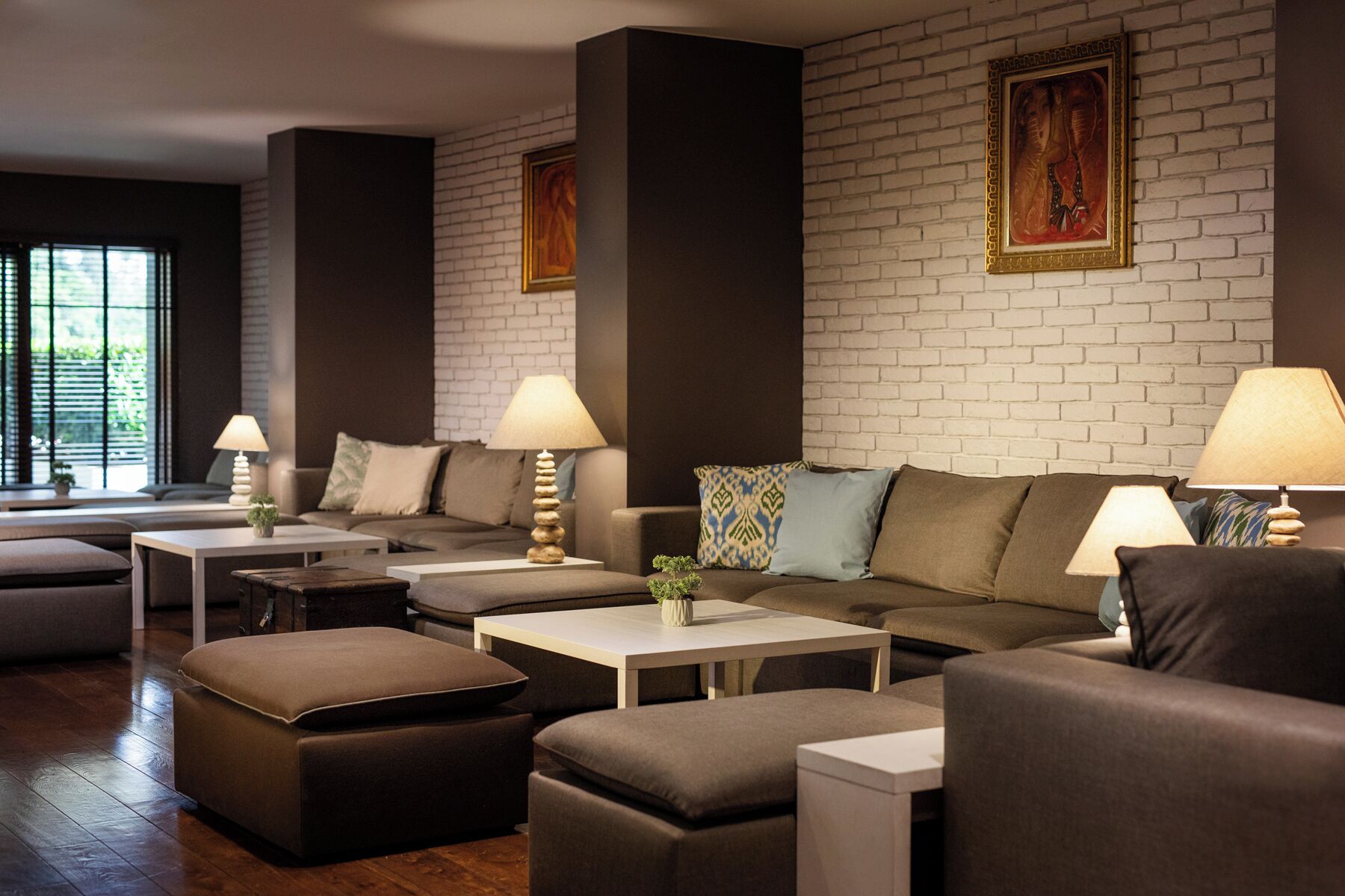 Un salon moderne avec un mur en briques, un ensemble de canapés, une table basse et une lampe.