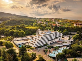 Um hotel moderno com vários andares, um pátio central e diversas piscinas.