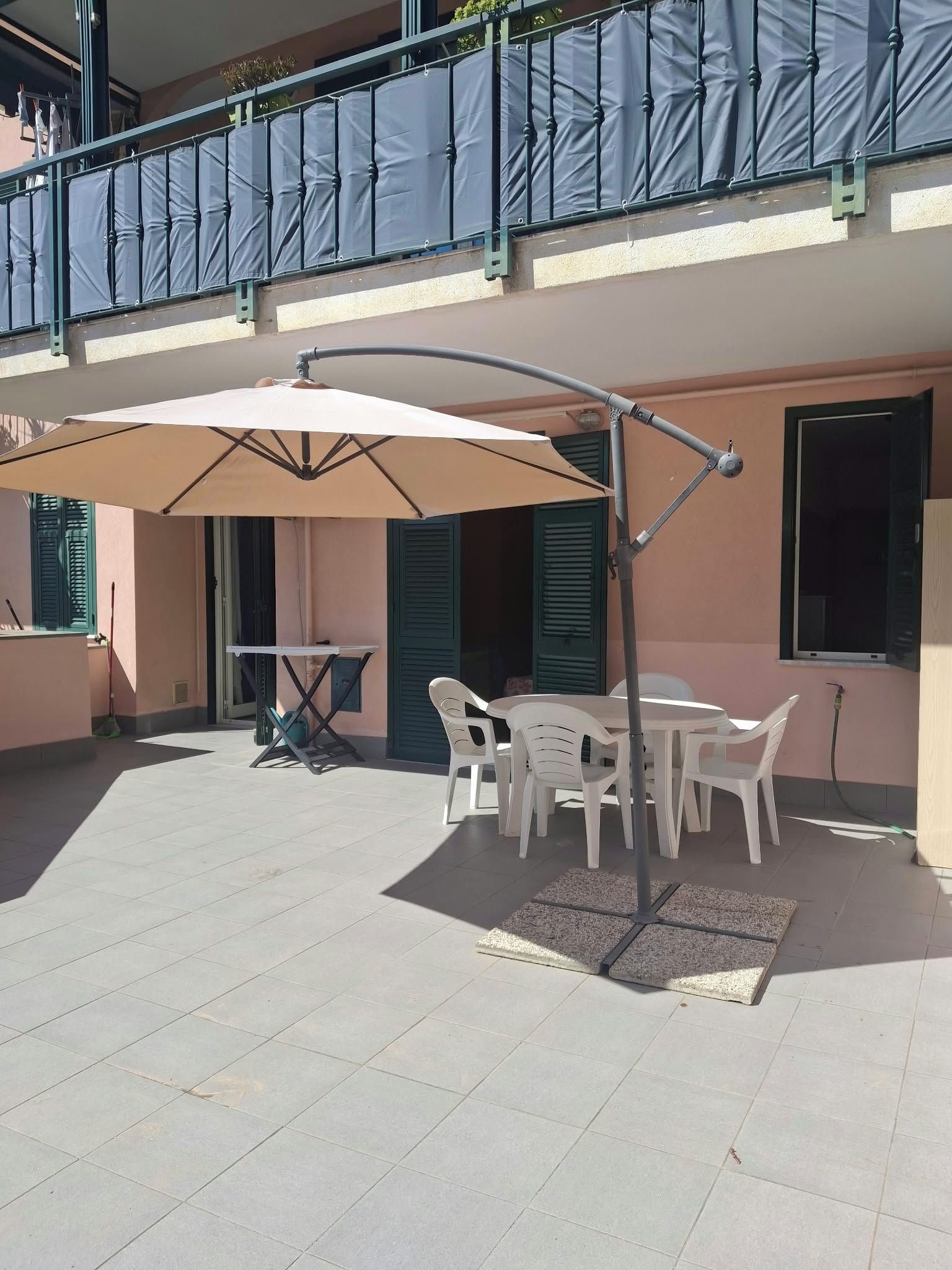 Une terrasse extérieure avec une table et des chaises, un parasol et un balcon doté d’une balustrade.