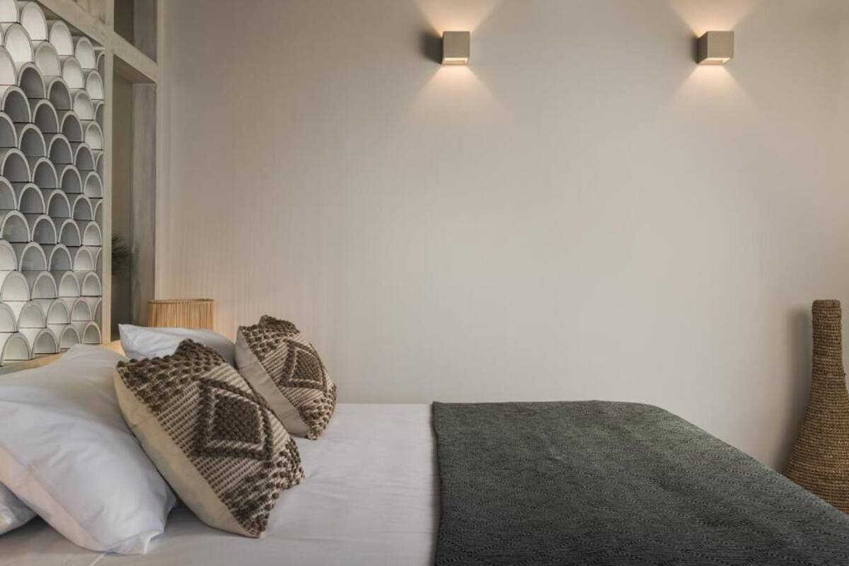 Relax in a stylishly designed room with a neatly made bed, patterned pillows, and a cozy throw blanket.