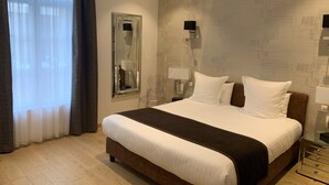 A hotel room with a large bed, a mirror, two bedside lamps, a nightstand, and a window with curtains. - Hotel Le Dome (Arras)