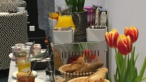 A breakfast buffet with various cheeses, meats, breads, and flowers. - Hotel Le Dome (Arras)