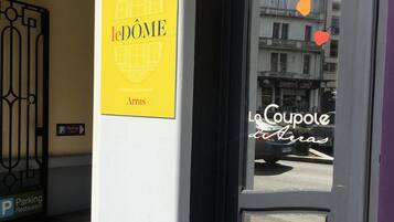 A hotel entrance with a sign reading "le DOME Hotel" and a "Parking Restaurant" sign.