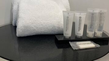Une table noire sur laquelle est posée une serviette blanche, trois tubes de lotion et un paquet de savon.
