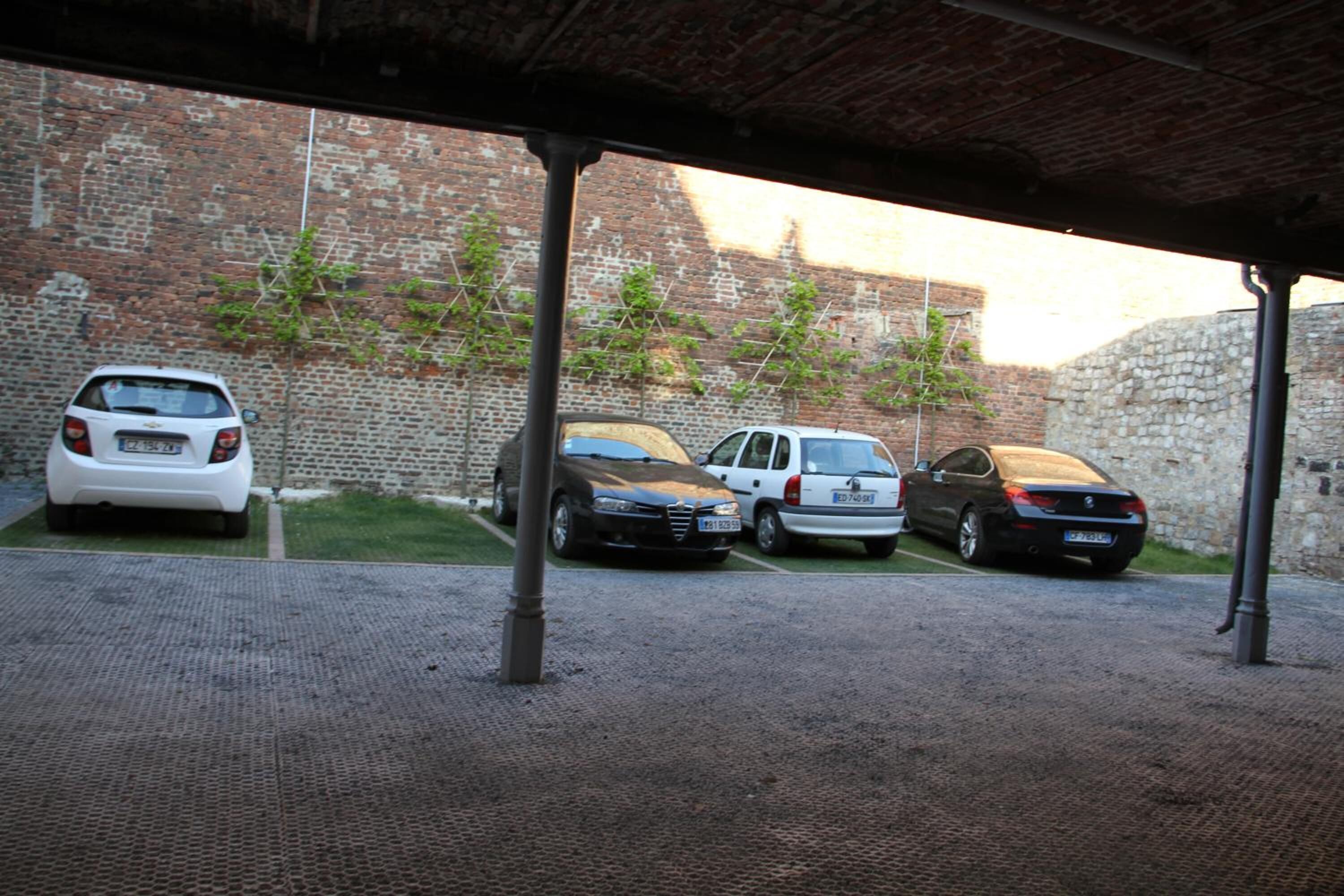 A covered parking area with four cars parked in a row.