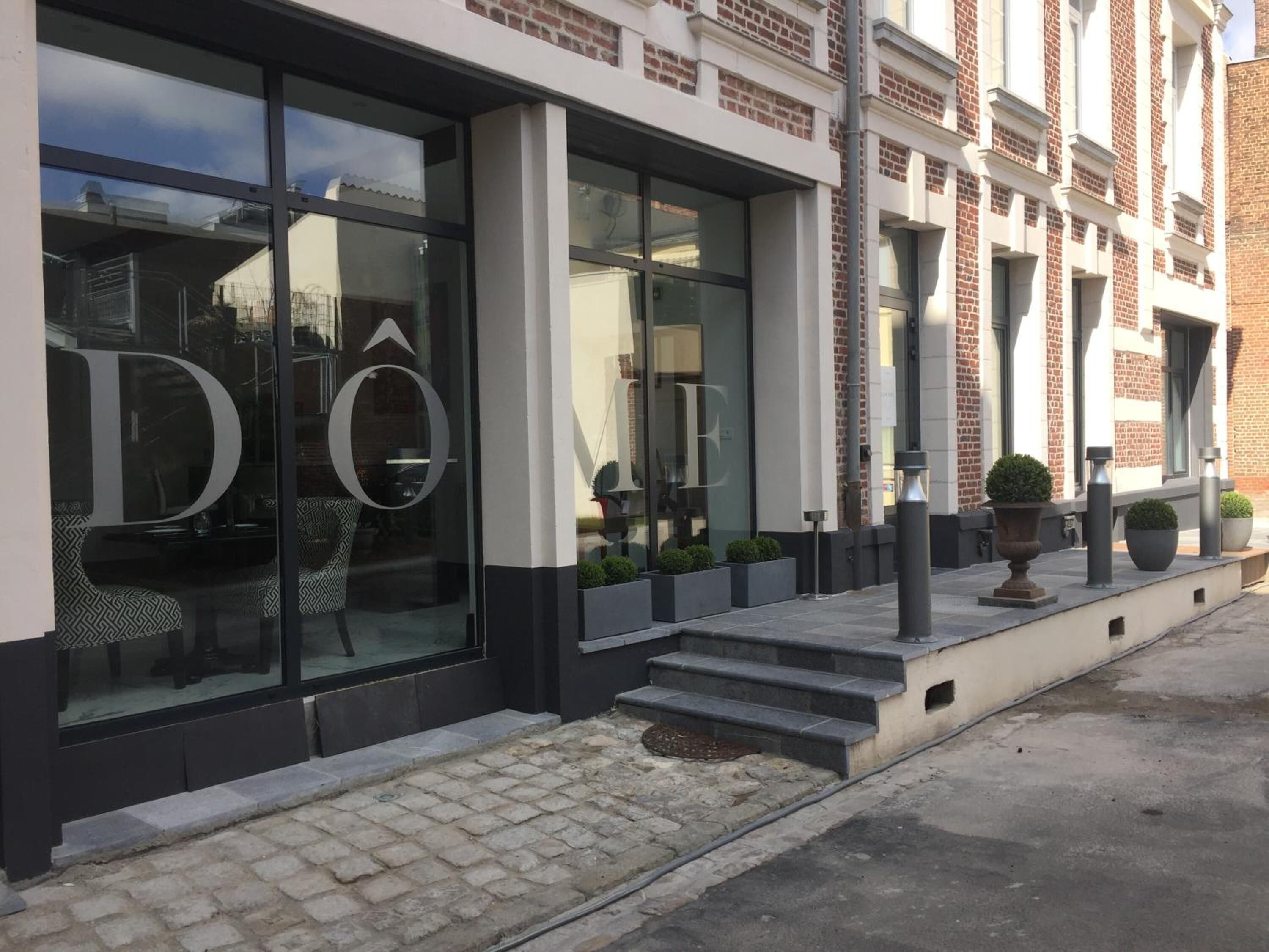 Ein modernes Gebäude mit großen Glasfenstern, einem auffälligen 'D'-Logo und einer Ziegel-Fassade.