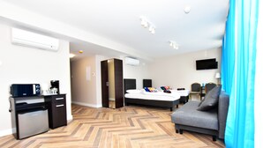 A hotel room with a bed, a sofa, a desk with a coffee machine, and a TV. - DUKES Apartments - Old Town (Wroclaw)