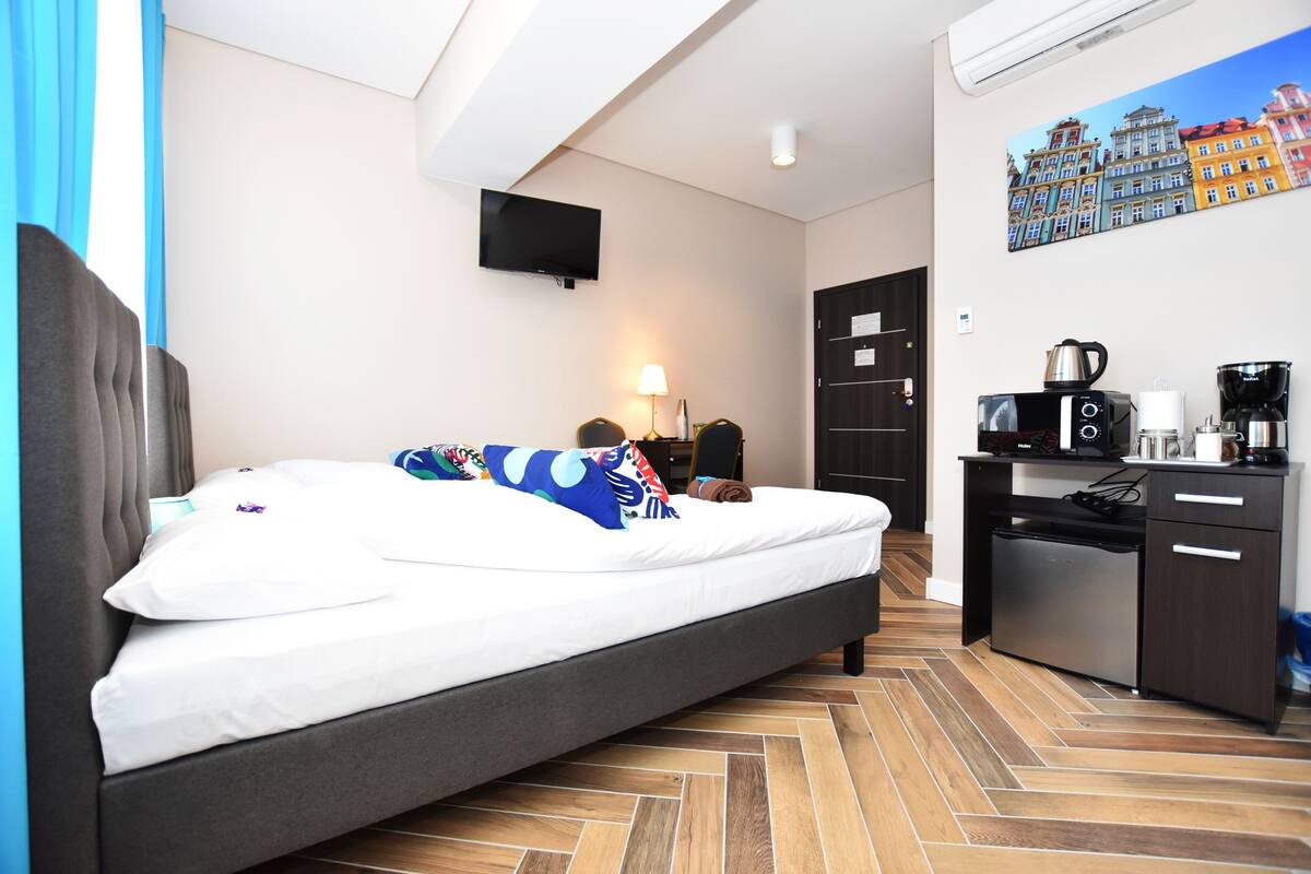 A modern hotel room with a bed, a desk, a microwave, and a coffee maker.