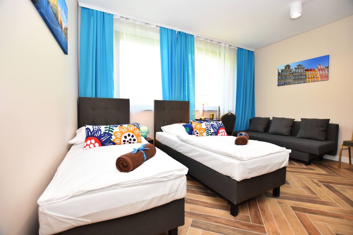A hotel room with two beds, a sofa, and a painting on the wall.