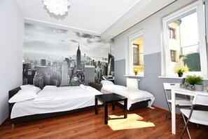Un dormitorio moderno con un mural de paisaje urbano, una cama, un escritorio y una silla.