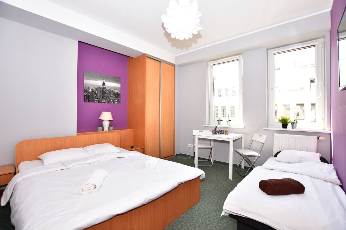 A hotel room with a bed, a desk, a chair, and a window.