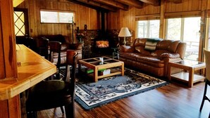 Een gezellig interieur van een chalet met een open haard, lederen meubels en houten balken.