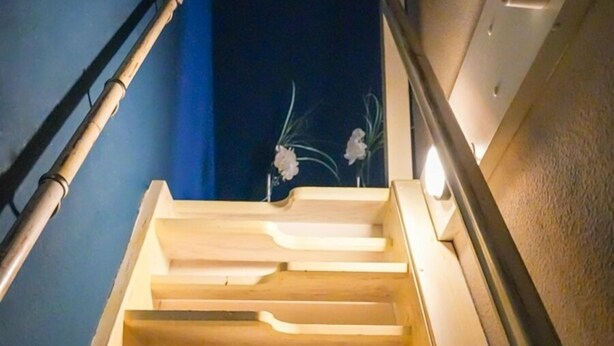 A wooden staircase with a handrail, leading to a dark area beyond. - Apartment Cajus - centrally located "Am Alten Strom" with quiet roof terrace (Warnemünde)