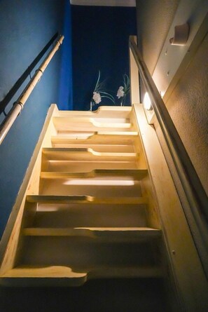 A wooden staircase with a handrail, leading to a dark area beyond. - Apartment Cajus - centrally located "Am Alten Strom" with quiet roof terrace (Warnemünde)