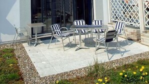 A modern house with a sloped roof, a large window, and a patio with outdoor furniture. - Apartment Cajus - centrally located "Am Alten Strom" with quiet roof terrace (Warnemünde)