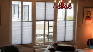 A room with a large window, a red chandelier, and a framed artwork on the wall. - Apartment Cajus - centrally located "Am Alten Strom" with quiet roof terrace (Warnemünde)
