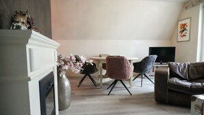 A living room with a fireplace, a television, two chairs, and a sofa. - Apartment Cajus - centrally located "Am Alten Strom" with quiet roof terrace (Warnemünde)
