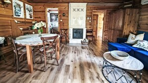 Interior acogedor de una cabaña con comedor, chimenea y sofá azul.