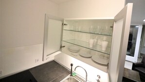 Ein modernes Badezimmer mit einer Glasablage für Tassen und Tellern, einem Waschbecken mit Armatur und einer Duschkabine.