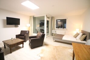 A modern living room with a flat-screen TV, leather armchairs, a sofa, a wooden coffee table, and a glass door leading to a balcony. - modern apartment in the center of Langenhagen (Langenhagen)