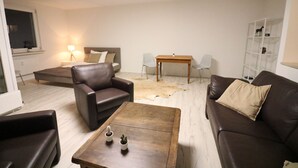 Ein Wohnzimmer mit braunem Ledersofa, einem Holztisch und einem kleinen Tisch mit Stühlen.