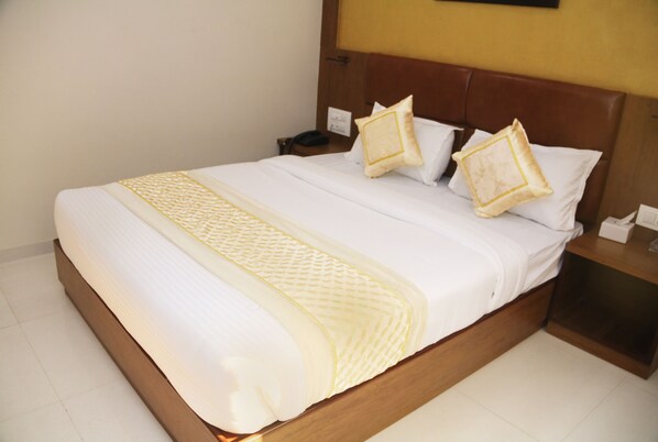 A neatly made bed with a wooden headboard, white bedding, and two decorative pillows.