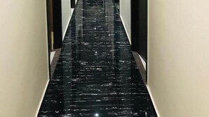 Un lungo e stretto corridoio con pavimento in marmo nero e pareti color crema.