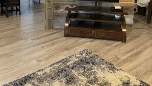 Un salon avec un mur en bois, un téléviseur à écran plat, une table basse en bois et un tapis.