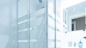 A modern bathroom with a glass-enclosed shower, a white sink, and a toilet. - El HostALL (Madrid)