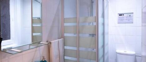 Un baño moderno con cabina de ducha de vidrio, un lavabo blanco y un inodoro.