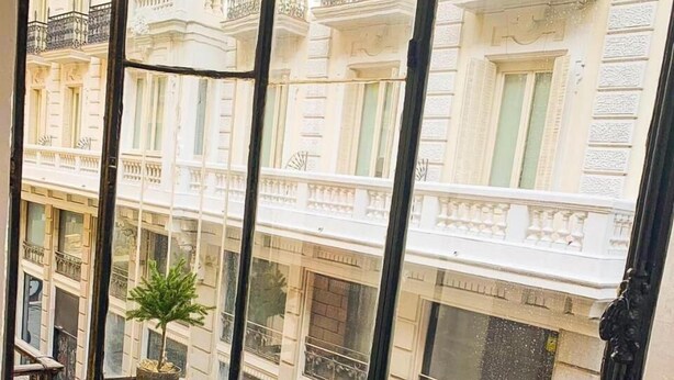 A balcony with ornate black metal railings and a potted plant. - El HostALL (Madrid)