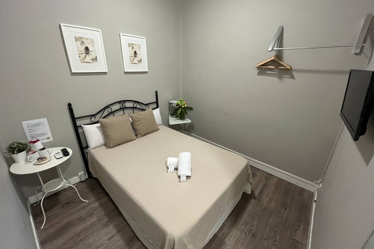 A neatly arranged bedroom with a bed, bedside table, and a small table with a plant.