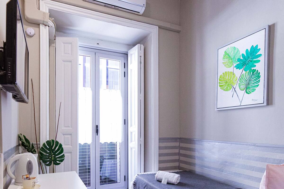 A modern bedroom with a bed, bedside table, and a view of the outside.