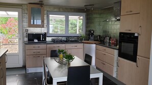Una cocina moderna con comedor, que incluye un microondas, estufa, fregadero y alacenas.