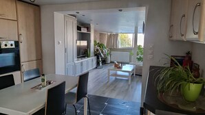 Una cocina moderna con comedor, horno empotrado y un amplio ventanal que deja entrar luz natural.
