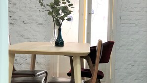 Ein Essbereich mit Tisch und Stühlen, eine Vase mit Pflanze und eine weiße Ziegelwand.
