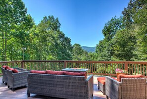 Eine Terrasse mit Korbmöbeln und Blick auf einen bewaldeten Bereich.