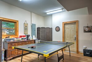 Ein Raum mit Tischtennisplatte, Dartscheibe, einer Holzeinrichtung für Gesellschaftsspiele und einer Tür mit Zahlenschloss.