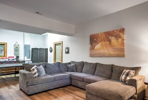 Ein modernes Wohnzimmer mit einer Eckcouch, einem Esstisch und einem großen Gemälde an der Wand.