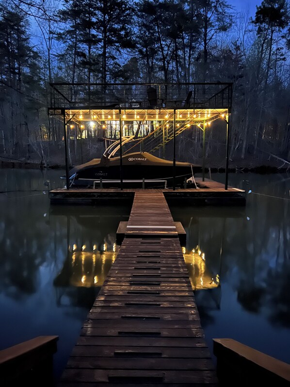 A dock leading to a covered area with a Cobalt logo, surrounded by a forested area.