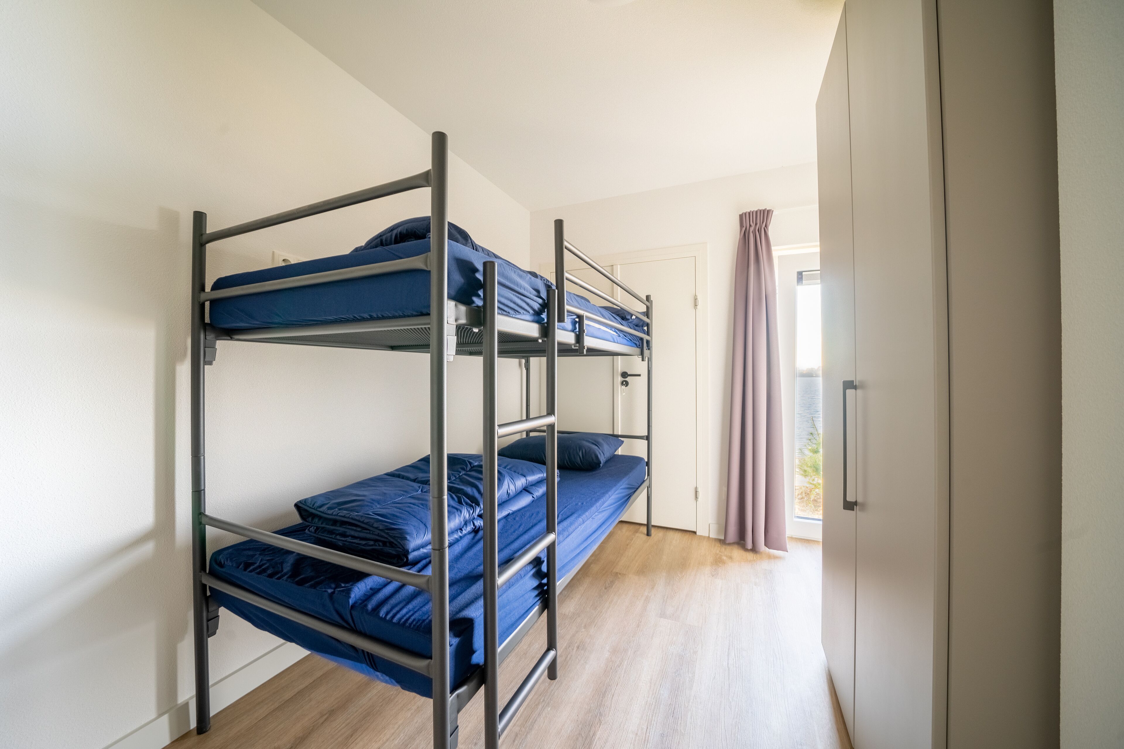 A bunk bed room with a door and a curtain.