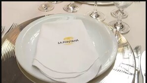 Een gedekte tafel met een wit bord met de tekst 'LA FONTAÑA' en bestek.