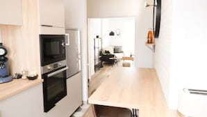A compact kitchen with a microwave, oven, and coffee maker. There is a wooden dining table and a chair. - ★★ Le Grand Chambord ★★ (Laval)