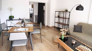 A modern living room with a sofa, a coffee table with a chessboard, and a dining area with a wooden table and chairs. - ★★ Le Grand Chambord ★★ (Laval)