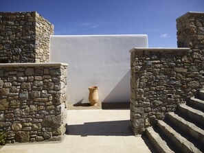 A stone wall with a white panel and a terracotta pot. - Bonzoe Suites & Villas (Mykonos)