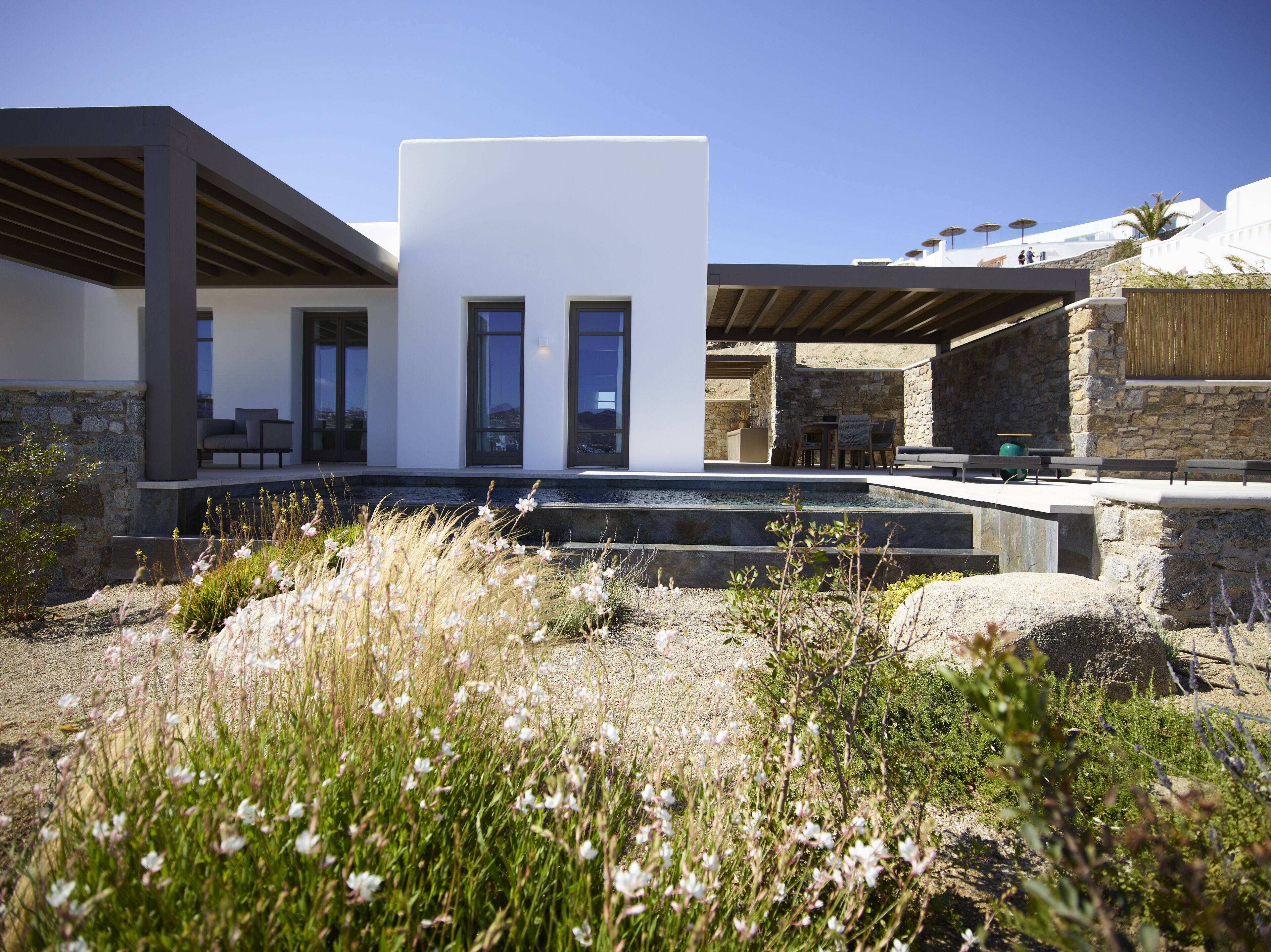 Et moderne hus med pool, stenvægge og udendørs siddepladser.