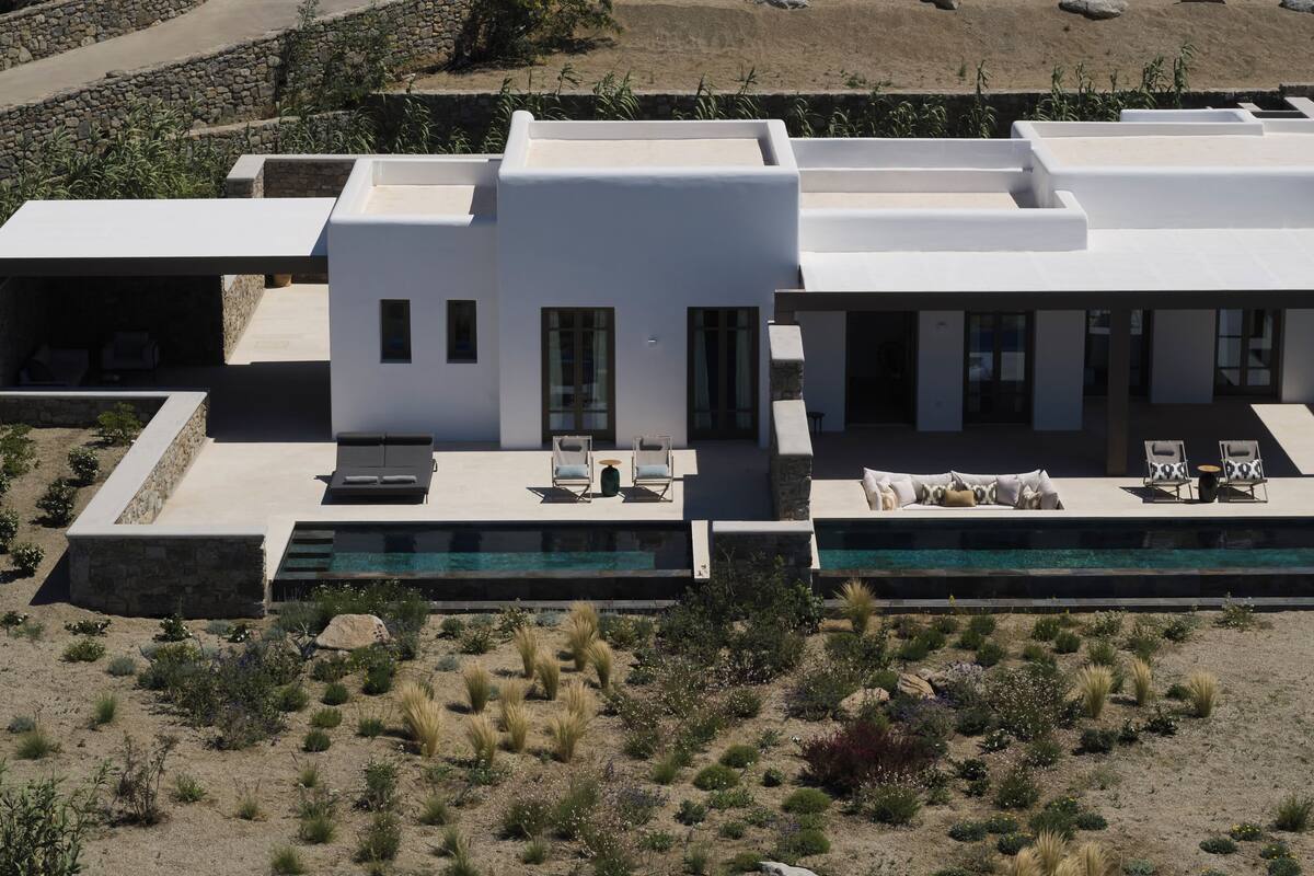 A modern house with a swimming pool, outdoor seating, and a desert landscape.